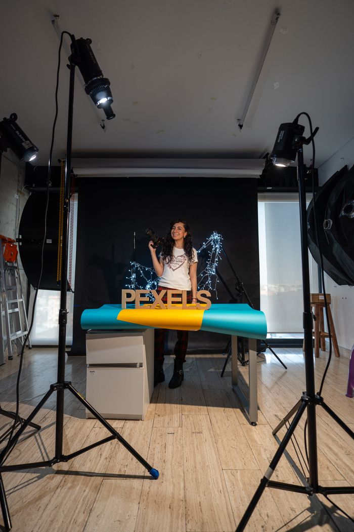 Young female photographer in a studio with lighting and backdrop setup.